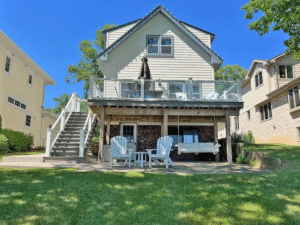 Close up of lake side of the home. Features a porch swing, large deck and patio